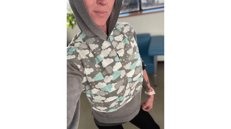 A person wearing a hoodie underneath a crop top vest that she designed and sewed and made herself fashion designer bodice block close fitting cloud computer SaaS clothing with Beyond ha ha photo 02 of 02